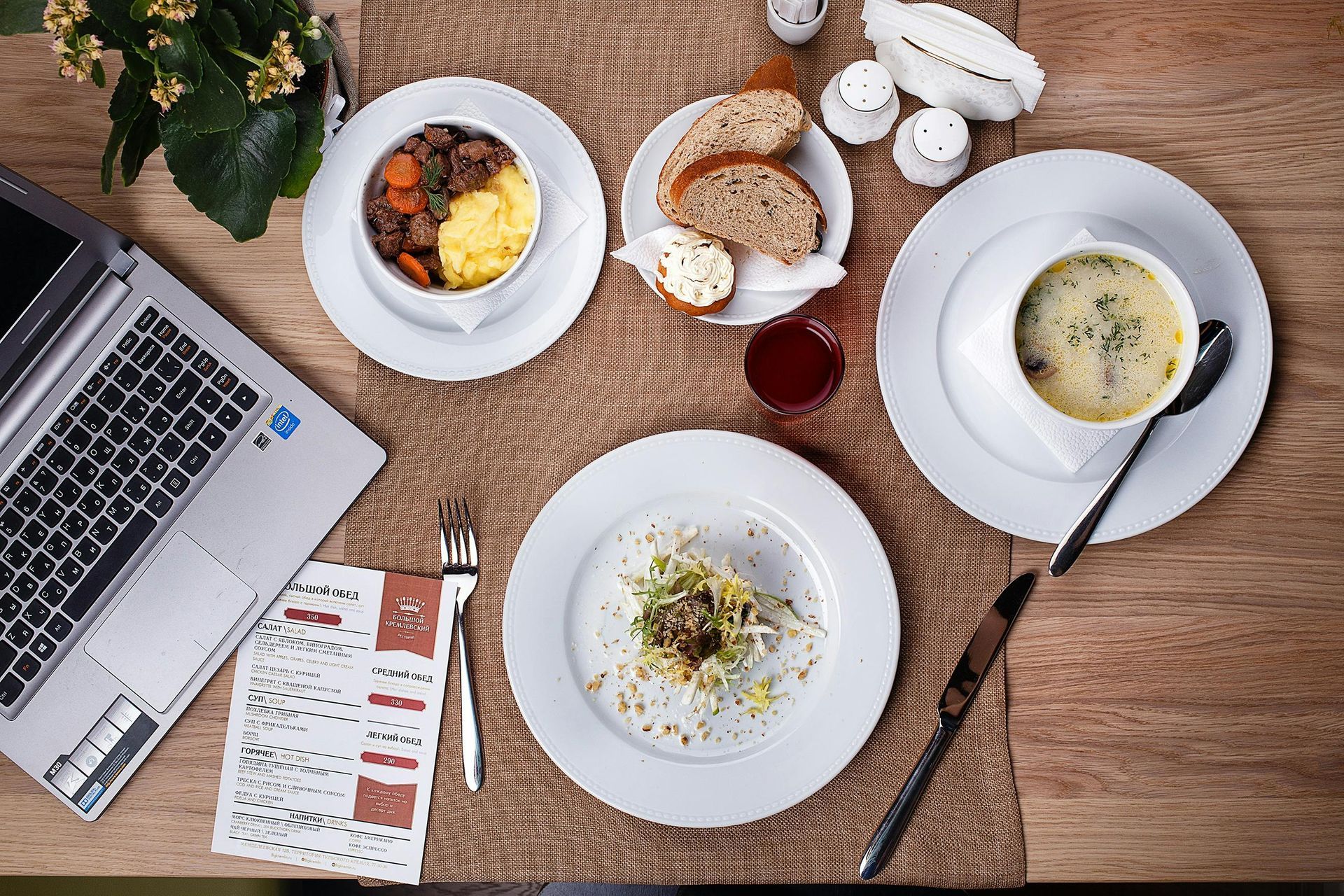 A table with plates of food and a laptop on it