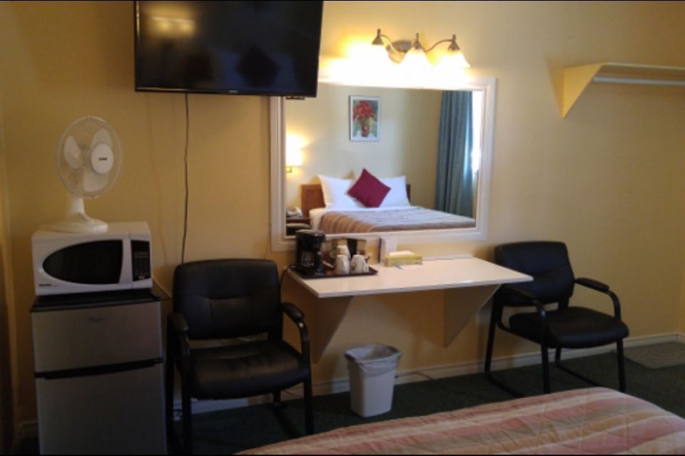 Hotel room with bed, desk, mirror, TV, microwave, mini-fridge, and two chairs.