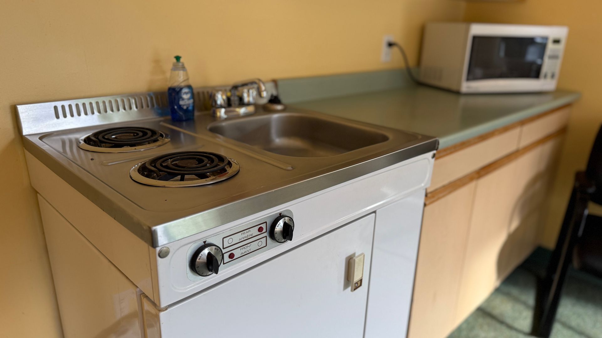Small kitchenette with a two-burner stove, sink, and microwave.