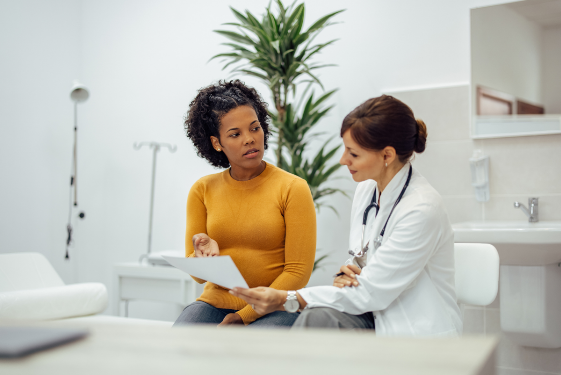 Doctor consulting with a patient in a bright clinic, reviewing paperwork together.
