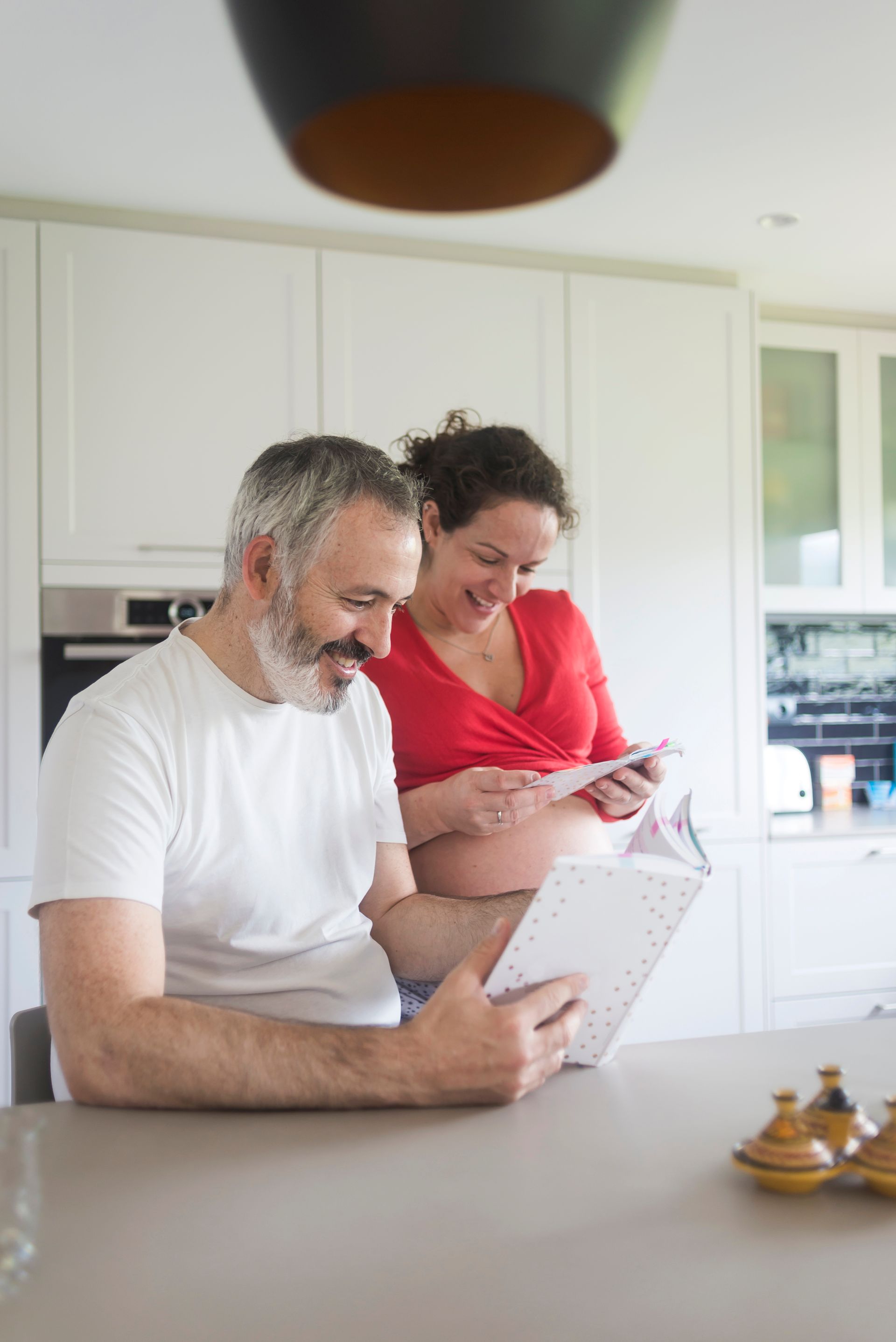 Two people in a bright kitchen looking at a tablet while standing by a counter.