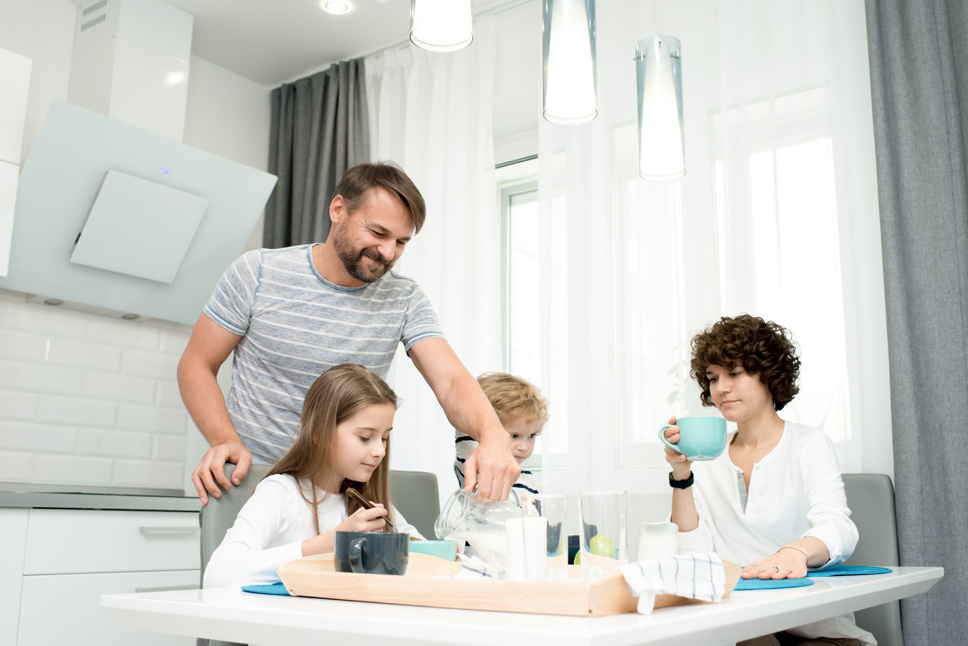 Family painting together at a table in a bright kitchen, with supplies and smiling faces