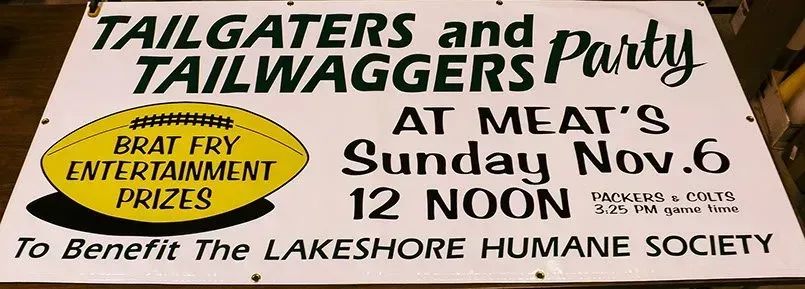 A sign for tailgate and tailwagger 's party at meat 's