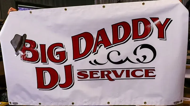 A person is holding a big daddy dj service banner