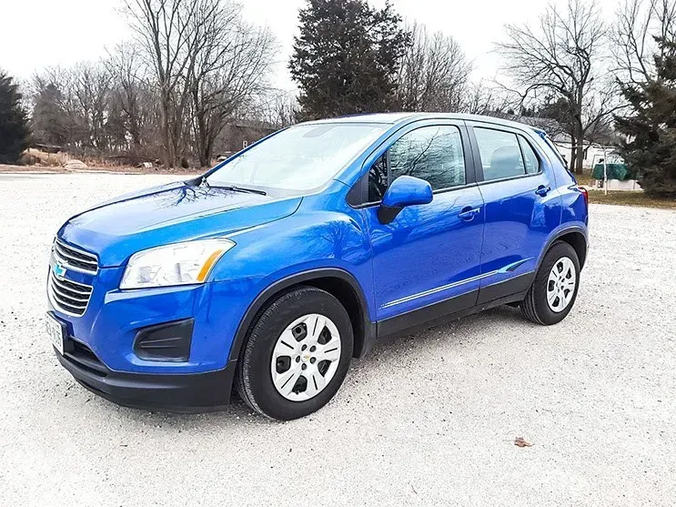 A blue chevrolet trax is parked in a gravel lot.