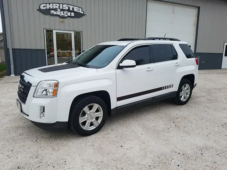 A white gmc terrain is parked in front of a building.
