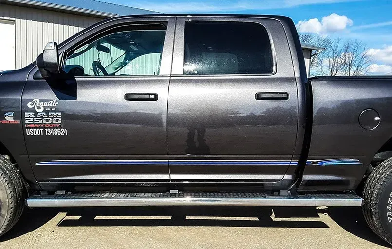 A gray dodge ram truck is parked in front of a building.