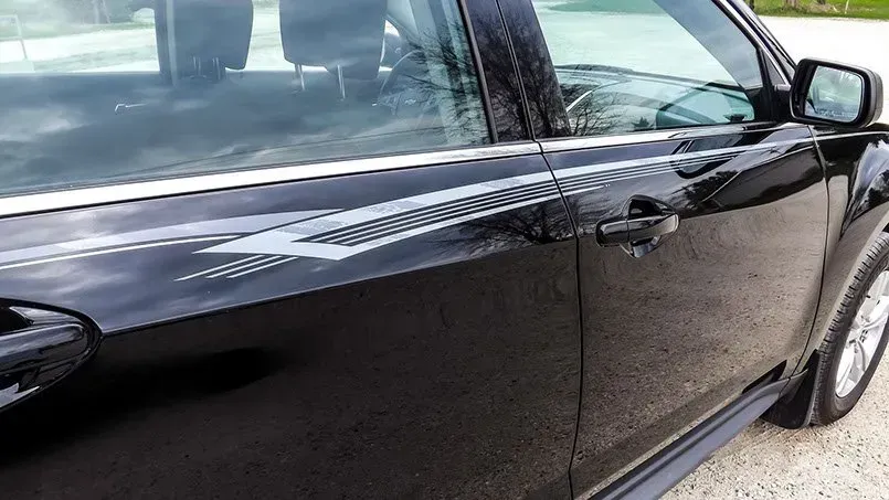 A black car with a white arrow on the side is parked on the side of the road.