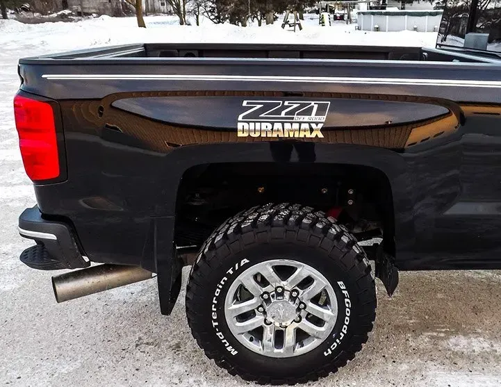 A black truck with a bfgoodrich tire is parked in the snow.