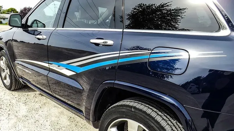 A black car with a blue stripe on the side is parked in a gravel lot.