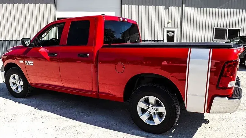 A red ram truck is parked in front of a building.