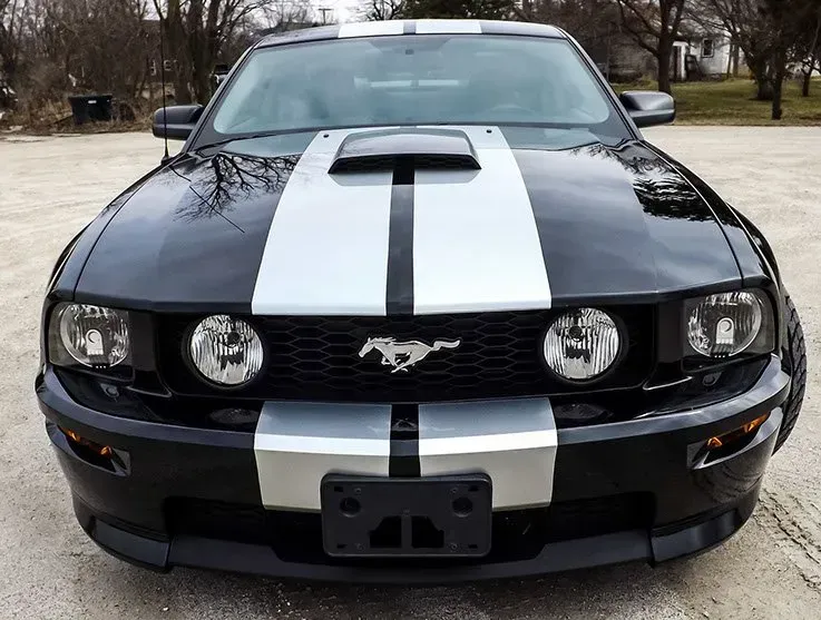 A black mustang with white stripes on the hood