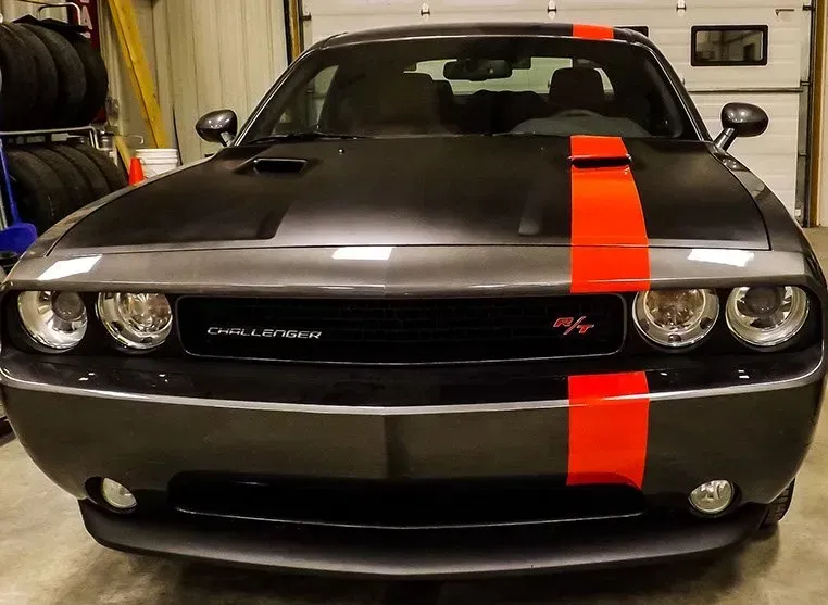 A black and red dodge challenger is parked in a garage