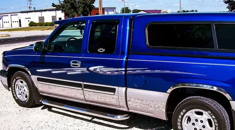 A blue truck is parked on a gravel road
