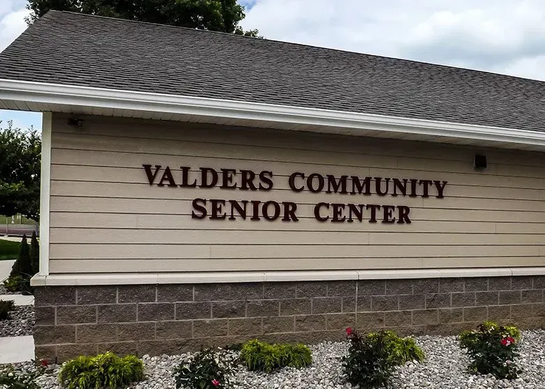 A sign for the valders community senior center is on the side of a building.
