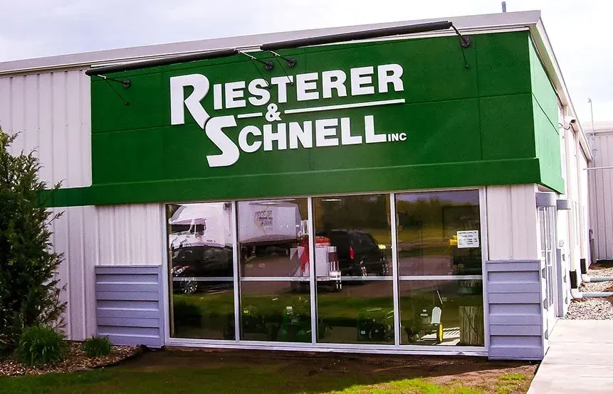 A white building with a green awning that says riester & schnell
