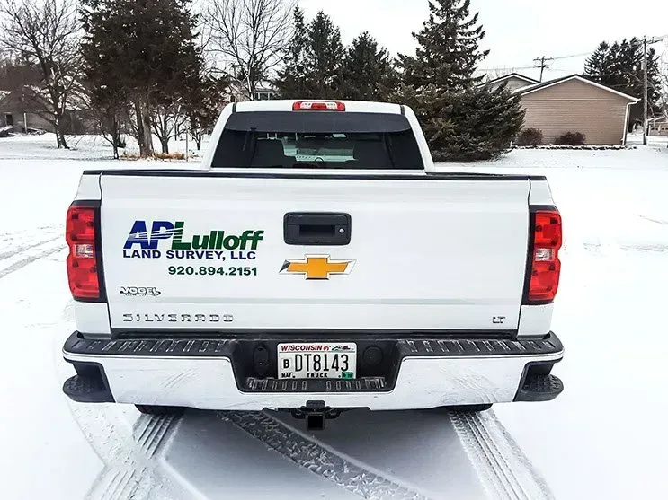 The back of a white truck is covered in snow.
