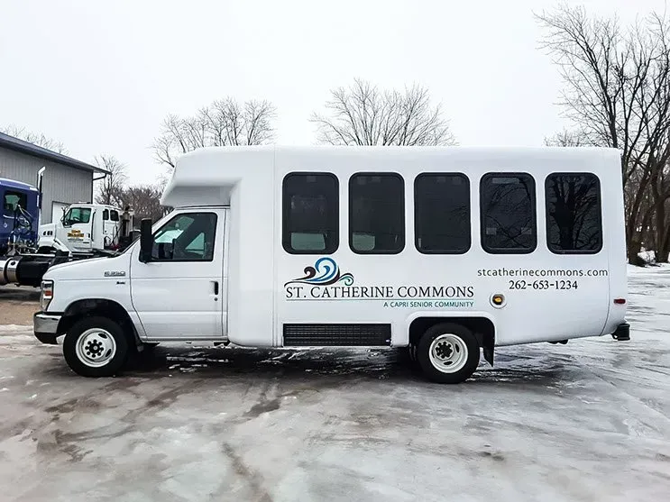 A white bus is parked in the snow in front of a building.