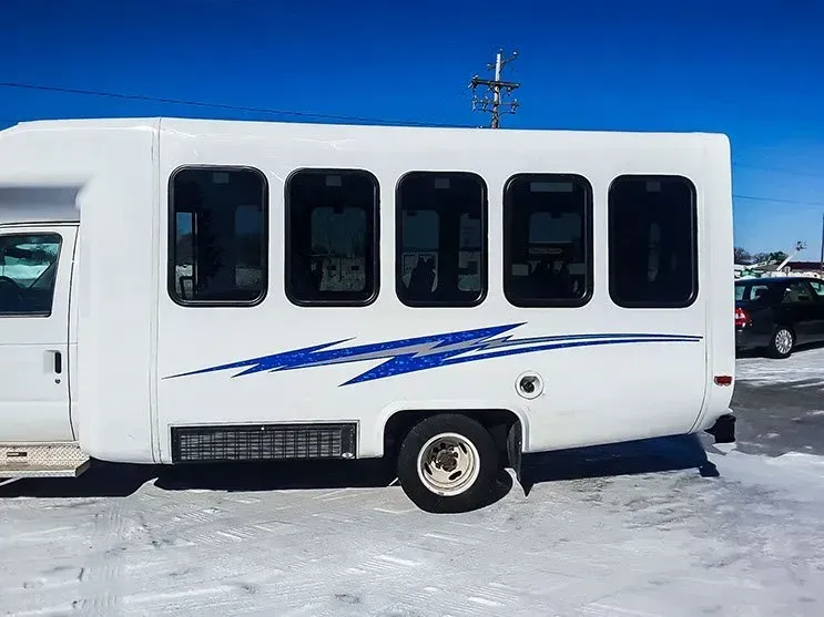 A white van is parked in the snow in a parking lot.