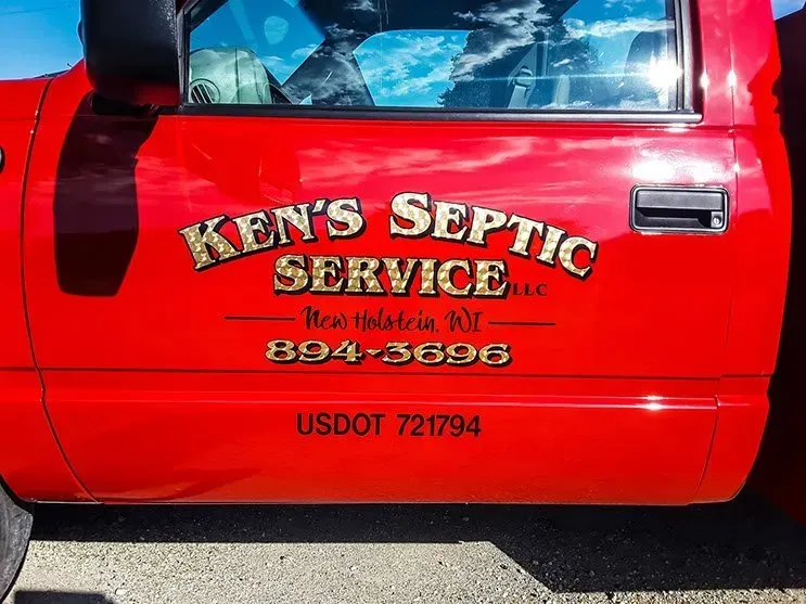 A red truck with ken 's septic service written on the side