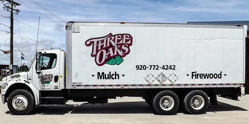 A white three oaks truck is parked on the side of the road.