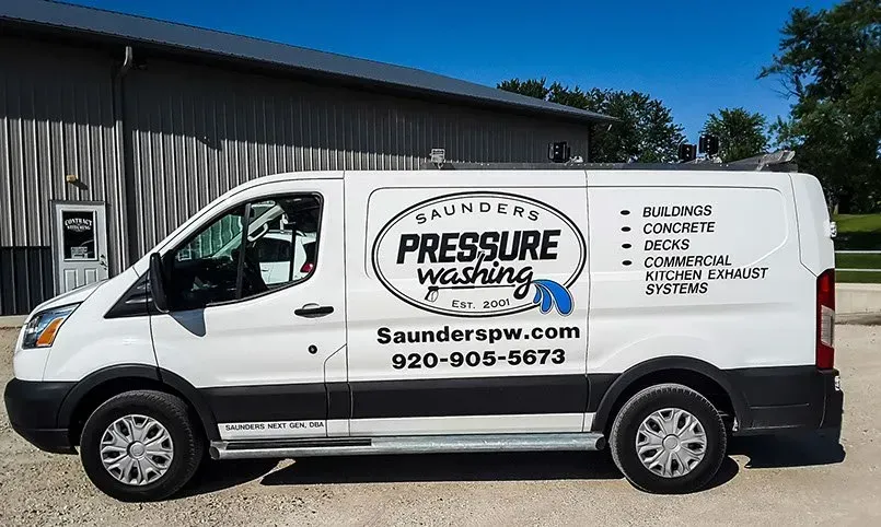 A white van for pressure washing is parked in front of a building.