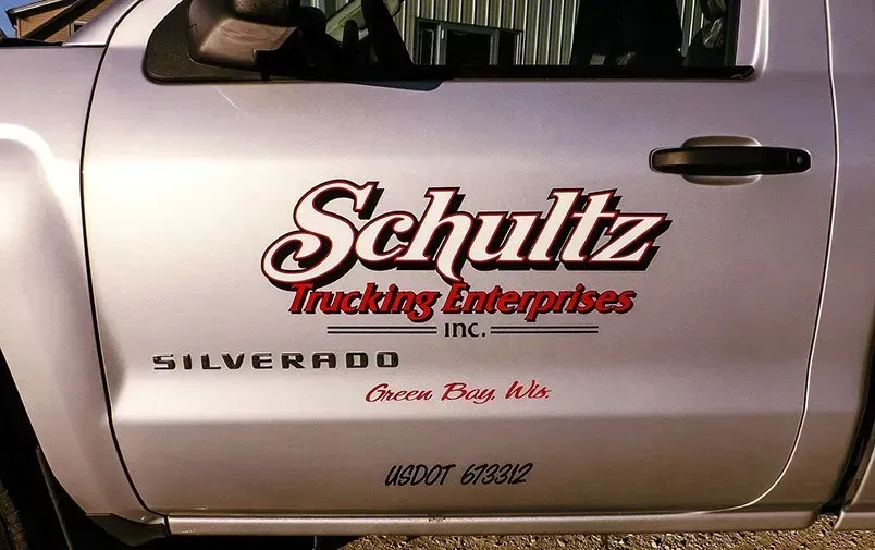 A silver truck with schultz trucking enterprises inc. written on the side
