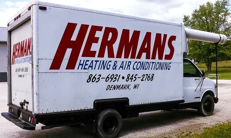 A hermans heating and air conditioning truck is parked on the side of the road
