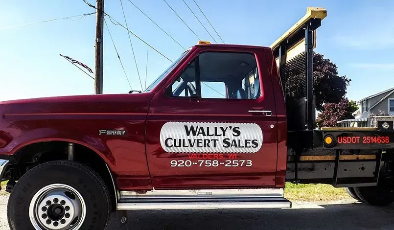 A red wally 's culvert sales truck is parked on the side of the road