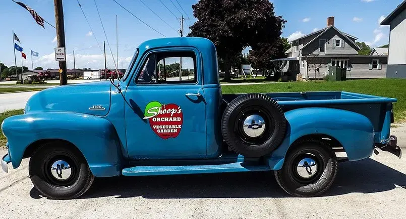 A blue truck is parked in front of a house