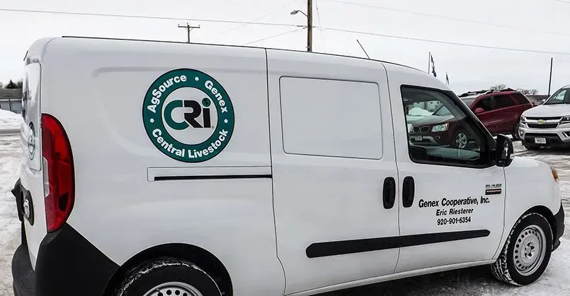 A white van with a green logo on the side is parked in the snow.