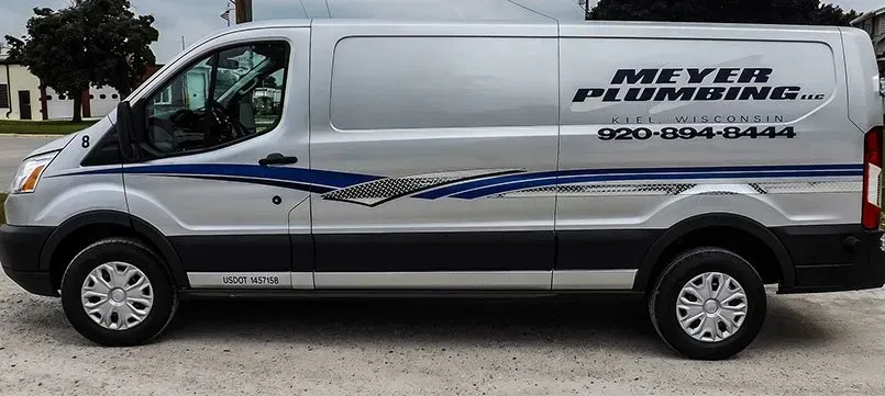 A silver van for meyer plumbing is parked in a parking lot.