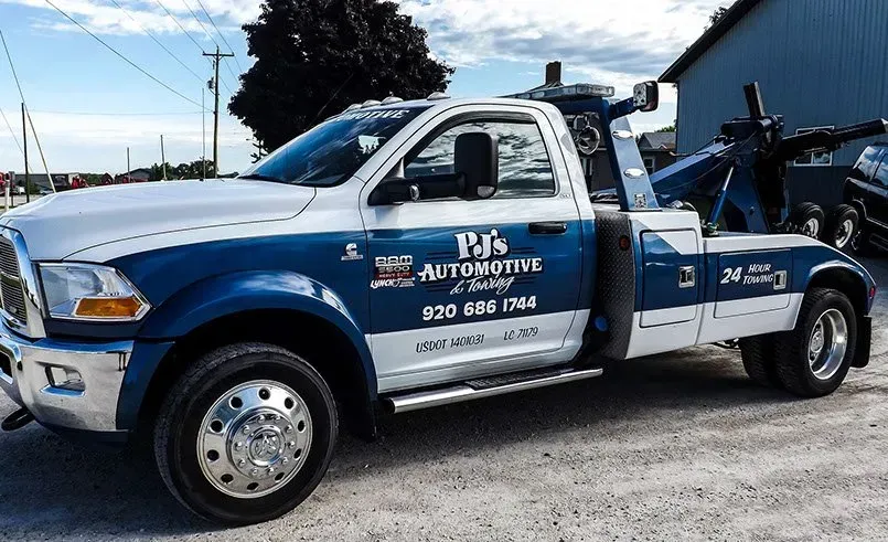 A blue and white tow truck is parked in front of a building.