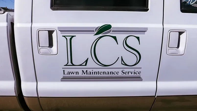 A white truck with lcs lawn maintenance service written on the side