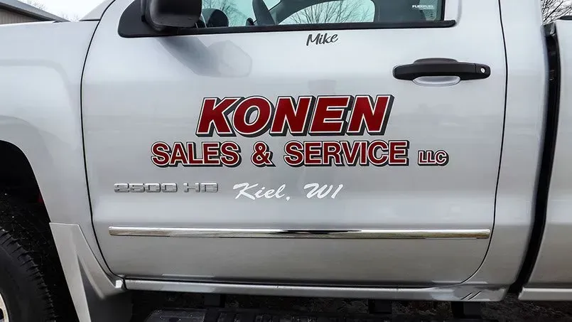 A silver truck with the word konen on the door