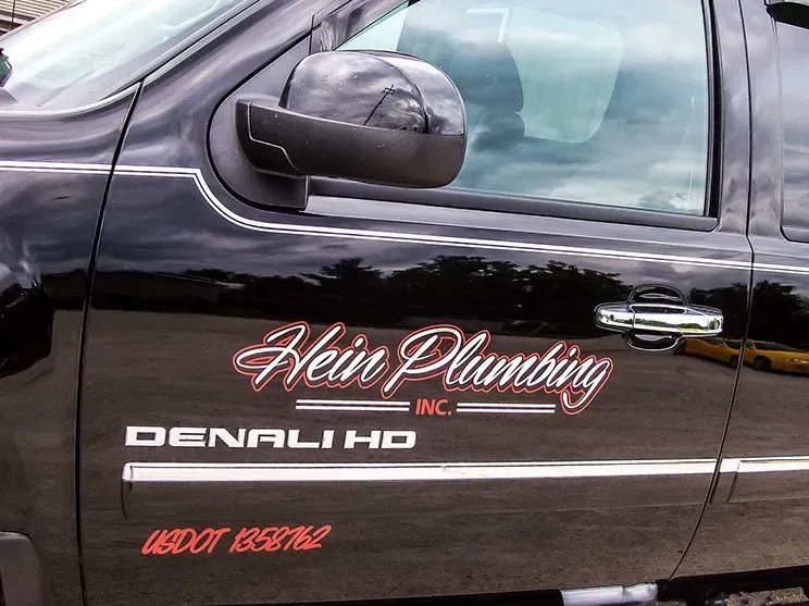 A hein plumbing truck is parked in a parking lot