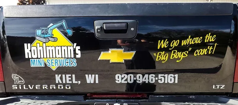 A black truck with a sticker on the back that says kohlmann 's mini services