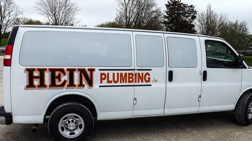 A white van for hein plumbing is parked in a parking lot