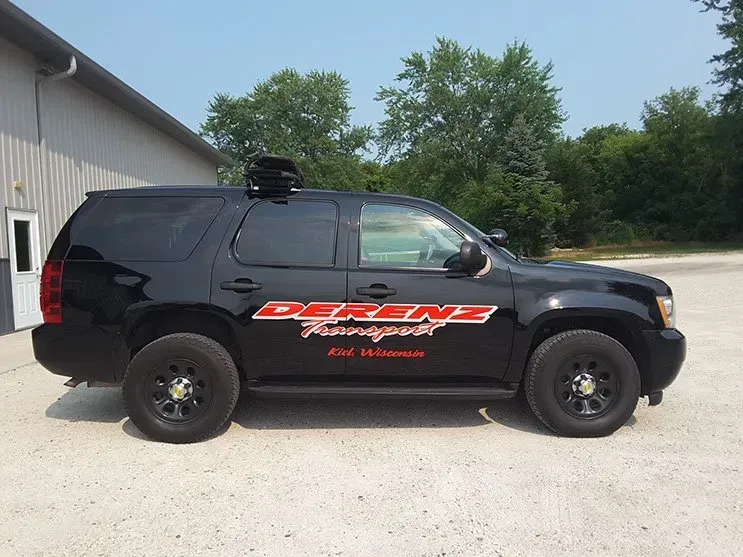 A black suv is parked in front of a building.