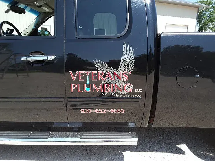 A black truck with veterans plumbing written on the side