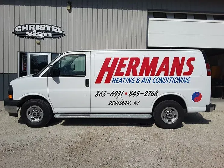A hermans heating and air conditioning van is parked in front of a building.