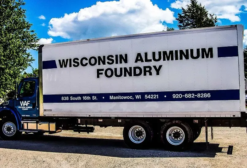 A wisconsin aluminum foundry truck is parked in a gravel lot