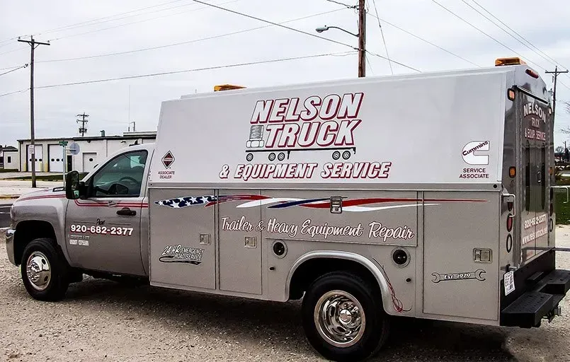 A nelson truck is parked in a gravel lot
