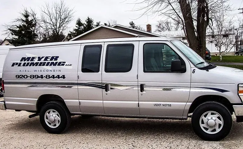 A meyer plumbing van is parked in front of a house