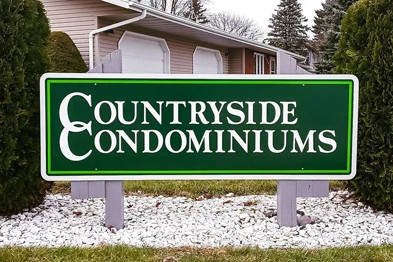 A green sign that says countryside condominiums in front of a house