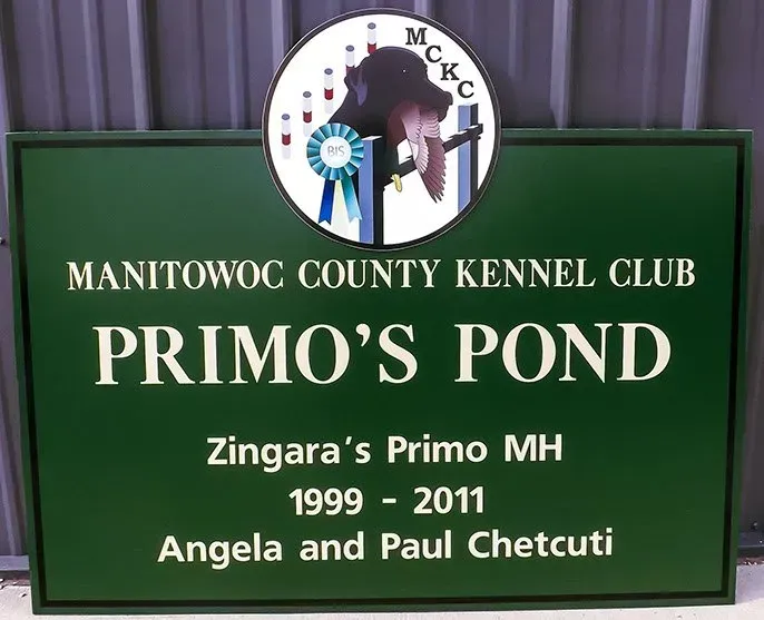 A green sign for manitowac county kennel club primo 's pond