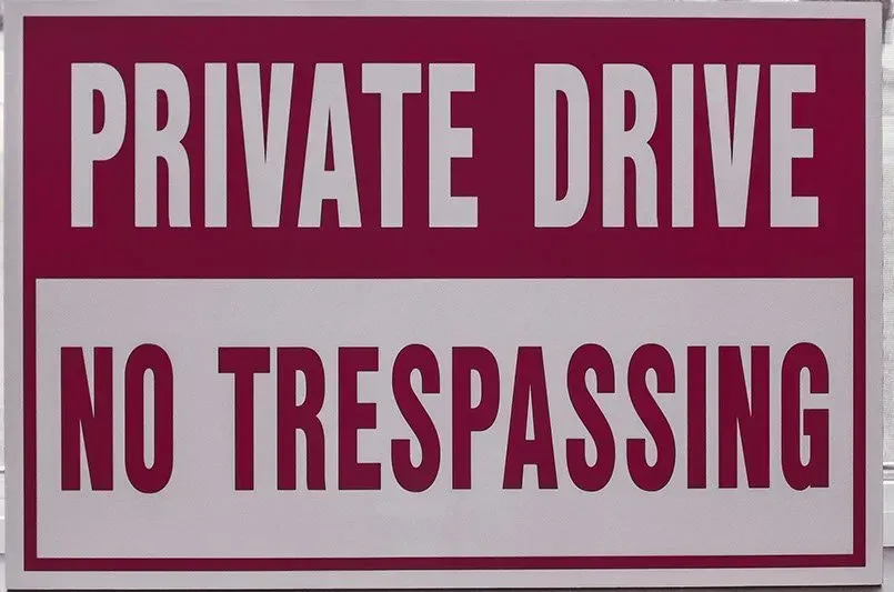 A red and white sign that says private drive no trespassing
