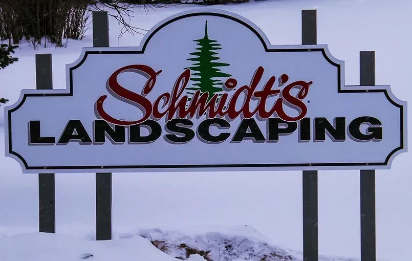 A sign for schmidt 's landscaping in the snow