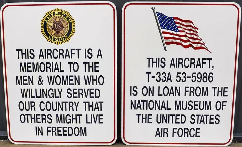 Two signs that say this aircraft is a memorial to the men and women who willingly served our country that others might live in freedom