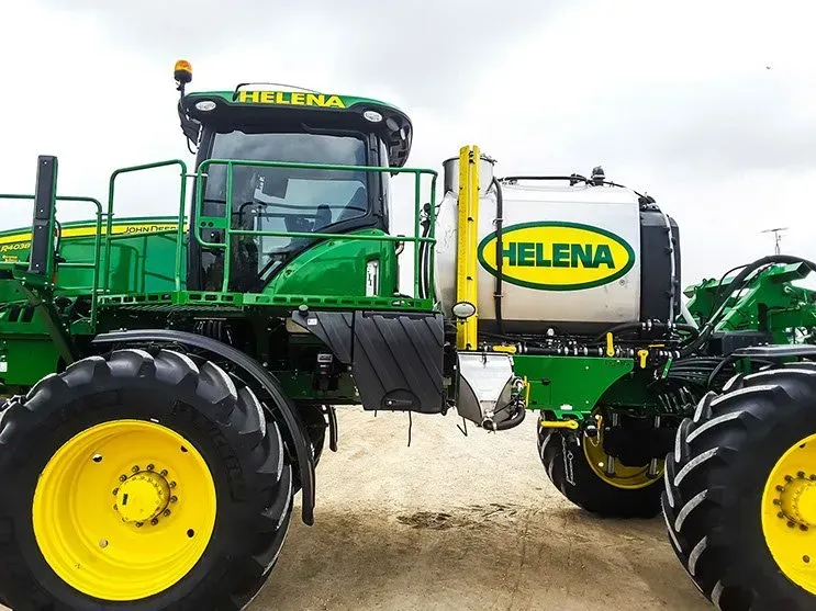 A green and yellow john deere tractor is parked in the dirt.